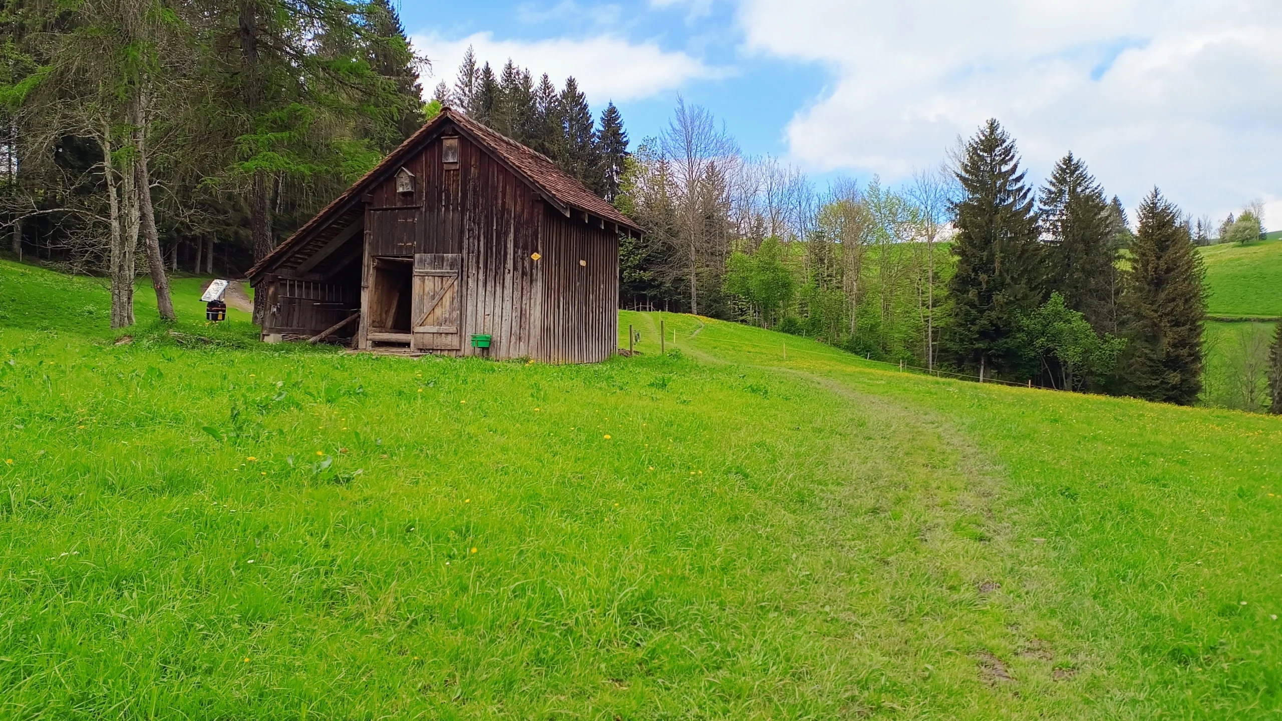 Wanderweg vorbei an einer Scheune durch eine Wiese